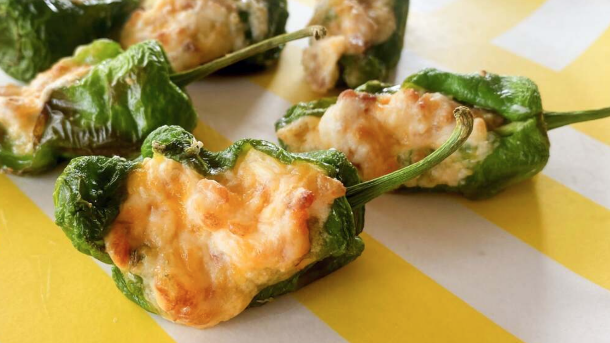 Shishito peppers stuffed with cheese on a plate.