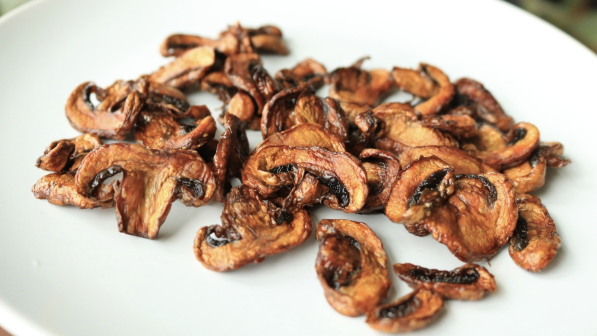 A pile of mushroom chips on a white plate.